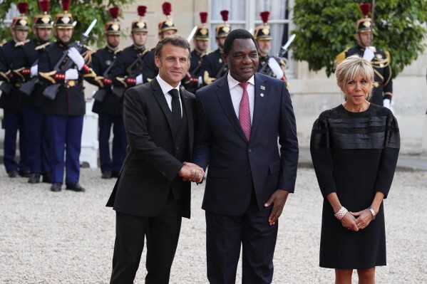 French President Emmanuel Macron and his wife Brigitte Macron welcome Hakainde Hichilema, centre, President of Zambia before dinner at the the Elysee Palace in Paris, Thursday, June 22, 2023. World leaders, heads of international organizations and activists are gathering in Paris for a two-day summit aimed at seeking better responses to tackle poverty and climate change issues by reshaping the global financial system. (AP Photo/Michel Euler)