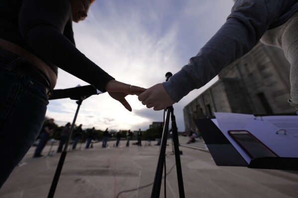 FILE - Benjamin Franklin High playwriting class students hold hands as they perform their play "The Capitol Project" on the steps of the Louisiana Capitol in Baton Rouge, La., March 27, 2024. Unlike recent years when there was an LGBTQ+ ally in the Louisiana governor's office, nothing stands in the way this year of legislation hostile to transgender people. Democratic former Gov. John Bel Edwards was able to block most such legislation in previous years through vetoes. Now conservative Republican Jeff Landry is in the governor's chair, and the legislation is advancing rapidly. (AP Photo/Gerald Herbert, File)