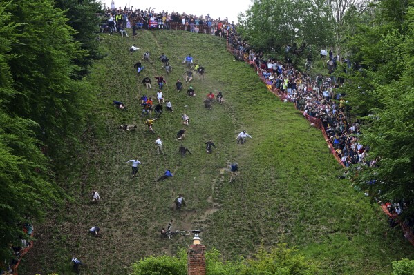Participants compete in the men's downhill race category of the traditional annual Cheese Rolling contest at Cooper's Hill in Brockworth, Gloucestershire, England, Monday, May 26, 2025.(AP Photo/Anthony Upton)