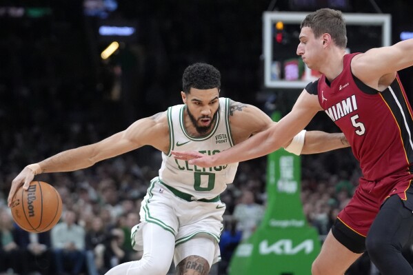 Boston Celtics forward Jayson Tatum (0) drives past Miami Heat forward Nikola Jovic (5) in the first half of Game 1 of an NBA basketball first-round playoff series, Sunday, April 21, 2024, in Boston. (AP Photo/Steven Senne)