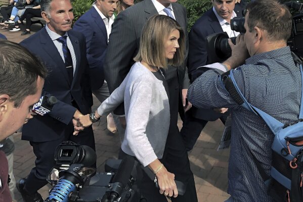 FILE -  In this Aug. 27, 2019 file photograph, actress Lori Loughlin departs hand in hand with her husband, clothing designer Mossimo Giannulli, left, in Boston, after a hearing in federal court in a nationwide college admissions bribery scandal. The couple say they're fighting the latest charges against them in the college admissions scandal. (AP Photo/Philip Marcelo)