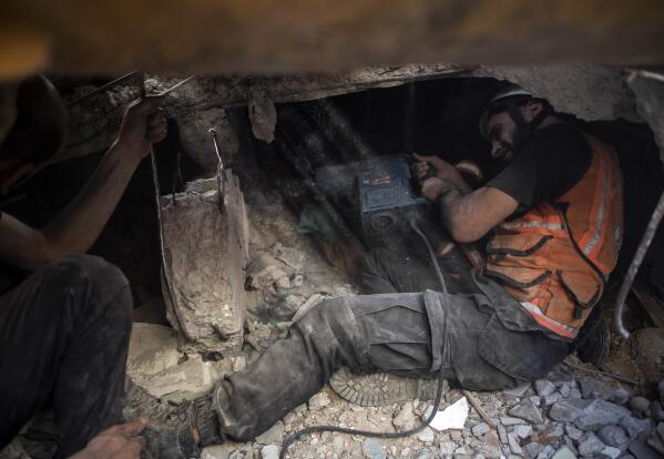 File - In this Sunday, May 16, 2021 file photo, Palestinian rescuers look for survivors under the rubble of on of the al-Kawlak destroyed residential buildings following deadly Israeli airstrikes in Gaza City. The single deadliest bombing raid of Israel's fourth war with Hamas collapsed two apartment buildings and killed 22 members of the extended al-Kawlak family, including a 6-month-old boy and his 89-year-old great-grandfather (AP Photo/Khalil Hamra,File)