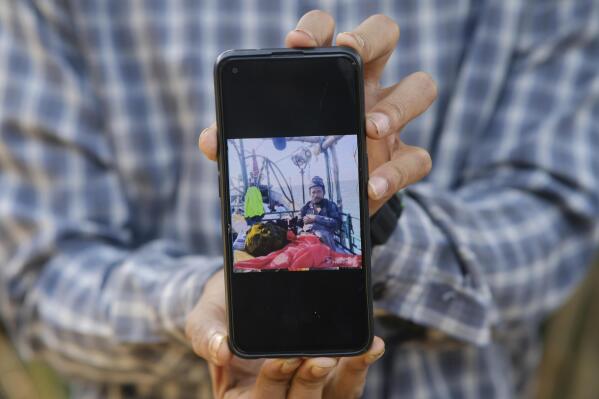 A man holds an undated photo of Jamal Hussein, who was the captain of a boat carrying around 180 Rohingya refugees that vanished in December, in Teknaf, part of the Cox's Bazar district of Bangladesh, on March 8, 2023. Back in Myanmar, Hussein was a rice farmer and a youth leader of his village. After his dad died, he became a father figure to his younger siblings, including his little sister, Bulbul. Their life in the camps was difficult, she recalls, but they managed. More recently, though, Jamal had received death threats, and started making plans to get out, Bulbul says. (AP Photo/Mahmud Hossain Opu)