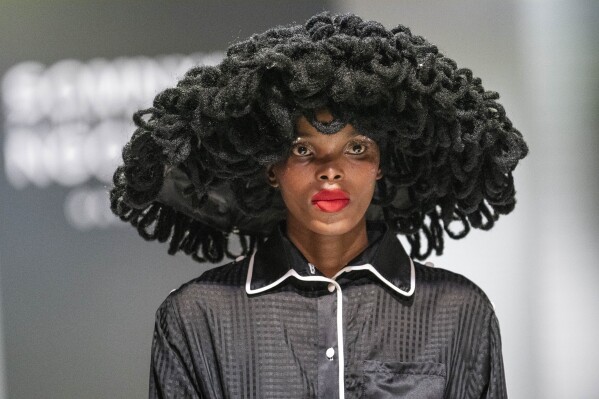 A model display a garment donated by selected designers for the "Design for Life" showcase opening the Johannesburg Fashion Week 2023 in Johannesburg, South Africa, Wednesday, Nov. 8, 2023. The primary objective of this show was to raise awareness for breast cancer, and many of the models were breast cancer survivors. (AP Photo/Jerome Delay)