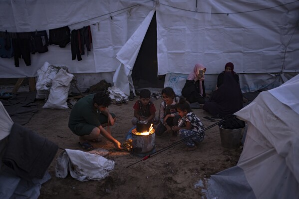 Palestinians displaced by the Israeli bombardment of the Gaza Strip sit by a fire in a UNDP-provided tent camp in Khan Younis, Tuesday, Oct. 31, 2023. (AP Photo/Fatima Shbair)
