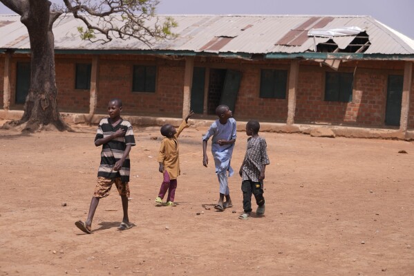 Children walk past classrooms at the LEA Primary and Secondary School Kuriga where students were kidnapped in Kuriga, Kaduna, Nigeria, Saturday, March 9, 2024. Security forces swept through large forests in Nigeria's northwest region on Friday in search of nearly 300 children who were abducted from their school a day earlier in the West African nation's latest mass kidnap which analysts and activists blamed on the failure of intelligence and slow security response. (AP Photo/Sunday Alamba)