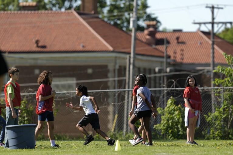 Students at Williams Science and Arts Magnet school play a game Friday, May 10, 2024, in Topeka, Kan. The school is just a block from the former Monroe school, seen in the distance, which was at the center of the Brown v. Board of Education Supreme Court ruling ending segregation in public schools 70 years ago. (AP Photo/Charlie Riedel)