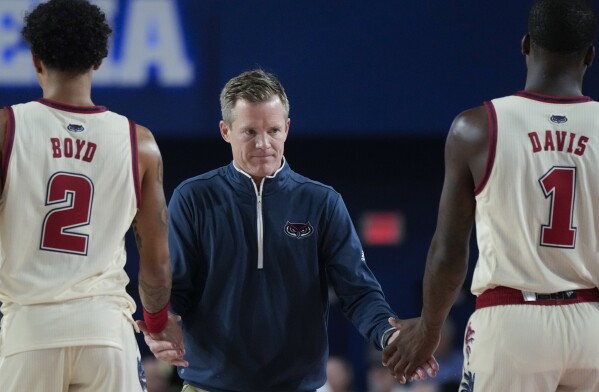 FILE - Florida Atlantic head coach Dusty May claps hands with guards Johnell Davis (1) and Nicholas Boyd (2) during the first half of an NCAA college basketball game, Nov. 14, 2023, in Boca Raton, Fla. May's hiring was announced Sunday, March 24, 2024 by Michigan, a move that brings him back to his Big Ten roots and ends his six-season stint that included a Final Four run a year ago at Florida Atlantic. (AP Photo/Rebecca Blackwell, file)