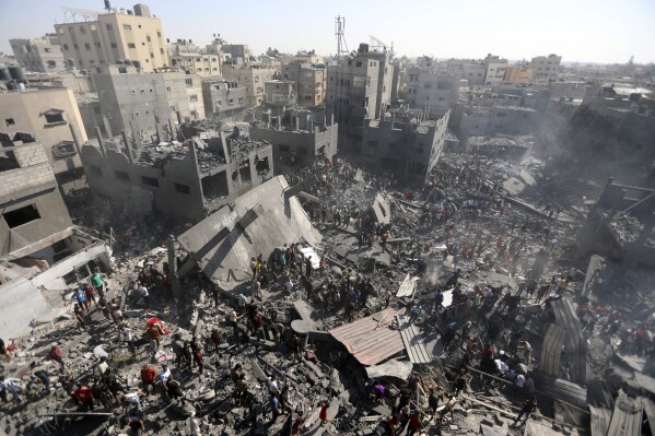 Palestinians inspect the rubble of destroyed buildings following Israeli airstrikes on the town of Khan Younis, southern Gaza Strip, Thursday, Oct. 26, 2023. (AP Photo/Mohammed Dahman)