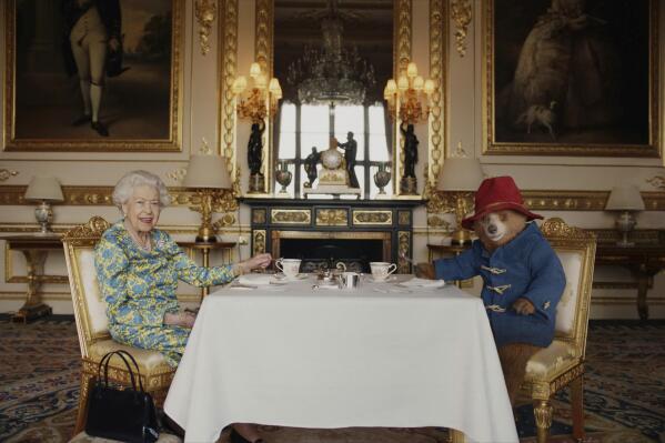 In this undated photo provided by Buckingham Palace/ Studio Canal / BBC Studios / Heyday Films on Saturday, June 4, 2022, Queen Elizabeth II and Paddington Bear have cream tea at Buckingham Palace, in London, taken from a film that was shown at the BBC Platinum Party at the Palace. (Buckingham Palace/ Studio Canal / BBC Studios / Heyday Films via AP)