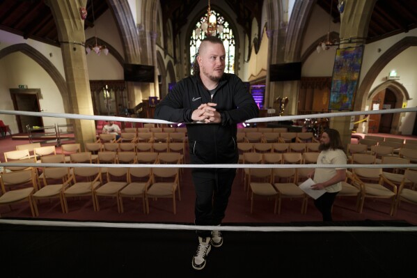 Gareth "Angel" Thompson, fundador de la organización benéfica Kingdom Wrestling, se encuentra en primera fila en la iglesia de San Pedro en Shipley antes de uno de los espectáculos mensuales de lucha libre de la organización, el sábado 29 de marzo de 2025. (Foto AP/Jon Super)