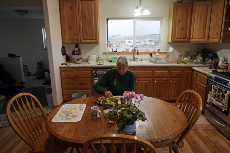 Gayna Salinas eats breakfast in her kitchen Thursday, Jan. 25, 2024, in Green River, Utah, with a view of an abandoned uranium mine behind her. (AP Photo/Brittany Peterson)