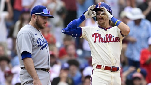 Philadelphia Phillies' Bryson Stott, right, reacts past Los Angeles Dodgers' Max Muncy after hitting a triple off relief pitcher Nick Robertson during the seventh inning of a baseball game, Sunday, June 11, 2023, in Philadelphia. (AP Photo/Derik Hamilton)