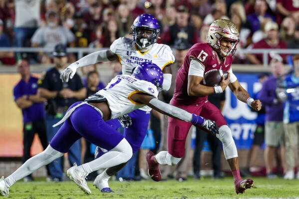 Florida State quarterback Jordan Travis runs as North Alabama's Demarcus Lacey Schultz (1) and Kam'ron Green (0) pursue during the first half of an NCAA college football game, Saturday, Nov. 18, 2023, in Tallahassee, Fla. Travis was injured later on the play. (AP Photo/Colin Hackley)