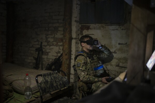 A Ukrainian soldier nicknamed Bakeneko wears a head-mounted display while operating an exploding drone from a basement in the outskirts of Kremmina, Ukraine, Sunday, Aug. 20, 2023. (AP Photo/Bram Janssen)