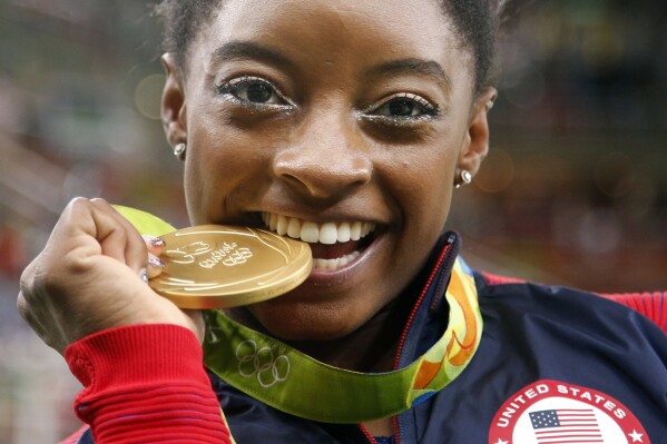FILE - United States' Simone Biles bites her gold medal for the artistic gymnastics women's individual all-around final at the 2016 Summer Olympics in Rio de Janeiro, Brazil, Aug. 11, 2016. USA Gymnastics announced Wednesday, June 28, 2023, that Biles, the 2016 Olympic champion, will be part of the field at the U.S. Classic outside of Chicago on Aug. 5. The meet will be Biles' first since the 2020 Olympics. (AP Photo/Dmitri Lovetsky)