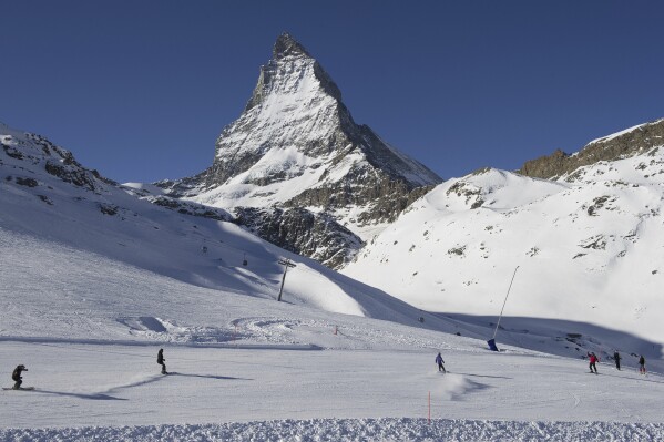 CORRECTS LOCATION FILE - Skiers ride down the slopes of the Zermatt ski resort with the Mount Matterhorn in the background, on Jan. 16, 2012, in Zermatt in the canton of Valais, Switzerland. An American teenager and two other people were killed in avalanche near the Swiss resort of Zermatt, police said Tuesday April 2, 2024. One person was flown to a hospital with serious injuries. (Jean-Christophe Bott/Keystone via AP, File)