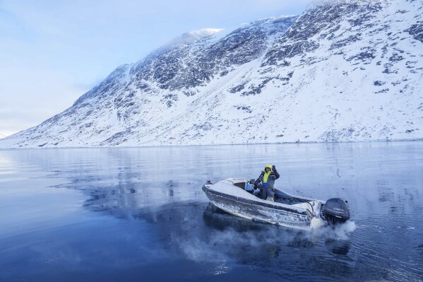 A fisherman rides on a boat though a frozen sea inlet outside of Nuuk, Greenland, Thursday, March 6, 2025. (AP Photo/Evgeniy Maloletka)