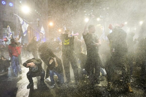 Police use water cannons to disperse demonstrators during a protest against Israeli Prime Minister Benjamin Netanyahu's government, and calling for the release of hostages held in the Gaza Strip by the Hamas militant group, in Tel Aviv, Israel, Saturday, Feb. 24, 2024. (AP Photo/Ohad Zwigenberg)