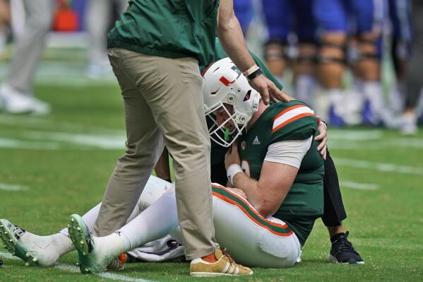 Miami quarterback Tyler Van Dyke (9) is helped on the field after he fumbled the ball as he was taken down by Duke linebacker Cam Dillon and defensive back Darius Joiner during the first half of an NCAA college football game, Saturday, Oct. 22, 2022, in Miami Gardens, Fla. (AP Photo/Wilfredo Lee)