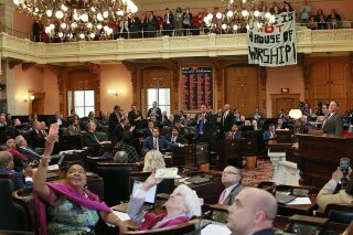 FILE - In this April 10, 2019 file photo, some members of the Ohio House applaud following their vote while others photograph protestors who unfurled banners reading "This is not a House of Worship" and "This is not a Doctor's office" following a vote on the Heartbeat Bill at the Ohio Statehouse in Columbus, Ohio.  A group of conservative lawmakers in Ohio has introduced a bill to outlaw abortion outright, declaring a fetus a person and subjecting doctors who terminate pregnancies to potential murder charges.  The legislation introduced Thursday, Nov. 14,  appears to make an exception for the life of the mother.(Brooke LaValley/The Columbus Dispatch via AP, File)