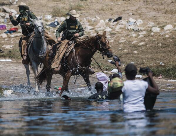 FILE - In this Sept. 19, 2021, file photo, U.S. Customs and Border Protection mounted officers attempt to contain migrants as they cross the Rio Grande from Ciudad Acuña, Mexico, into Del Rio, Texas. The Border Patrol's treatment of Haitian migrants, they say, is just the latest in a long history of discriminatory U.S. policies and of indignities faced by Black people, sparking new anger among Haitian Americans, Black immigrant advocates and civil rights leaders.( AP Photo/Felix Marquez, File)