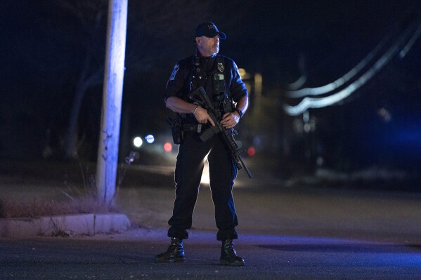 A police officer guards the road where the body of suspected mass shooter Robert Card was found, Friday, Oct. 27, 2023, in Lisbon, Maine. Despite warnings of deteriorating mental health, drunken threats and guns, the sheriff department chose to avoid confronting the Army reservist who later killed 18 people and work with family and the Army to get him help, states the report, released late Thursday, Dec. 14, 2023. (AP Photo/Robert F. Bukaty, File)