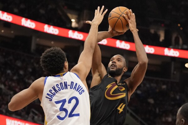 Cleveland Cavaliers forward Evan Mobley (4) shoots as Golden State Warriors forward Trayce Jackson-Davis (32) defends in the second half of an NBA basketball game, Friday, Nov. 8, 2024, in Cleveland. (AP Photo/Sue Ogrocki)