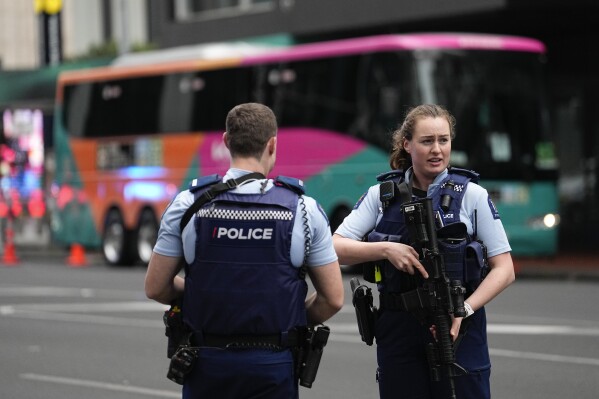 Armed New Zealand police officers stand outside a hotel housing a team from the FIFA Women's World Cup in the central business district following a shooting in Auckland, New Zealand, Thursday, July 20, 2023. New Zealand police are responding to reports that a gunman has fired shots in a building in downtown Auckland. (AP Photo/Abbie Parr)
