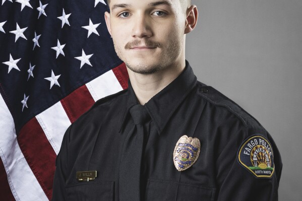 This photo provided by The City of Fargo, N.D., on Saturday, July 15, 2023 shows police officer Jake Wallin. On Saturday, Fargo's police chief said a gunman opened fire on police and firefighters as they responded to a traffic crash in North Dakota. One officer, Wallin, was killed and two others were wounded before a fourth officer killed him. (The City of Fargo via AP)