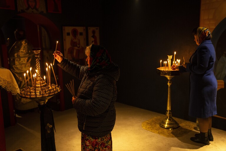 Orthodox Christian worshippers light candles during a ceremony at the Church of the Intercession in Lypivka, near Kyiv, Ukraine, Sunday, April 28, 2024. (AP Photo/Francisco Seco)