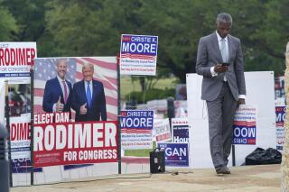 Volunteer Al Green looks at his phone as he takes a break from holding a sign supporting his candidate in a local election outside an early voting location Tuesday, April 27, 2021, in Mansfield, Texas. (AP Photo/LM Otero)