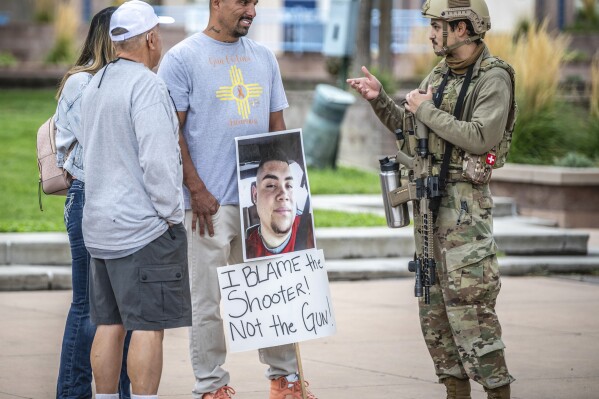 Luiz Otero, centre, holds a sign with his son Elias Otero's image, who was shot and killed a couple years ago in Albuquerque, N.M., as people attend a Second Amendment Protest in response to Gov. Michelle Lujan Grisham's recent public health order suspending the conceal and open carry of guns in and around Albuquerque for 30-days, Tuesday, Sept. 12, 2023, in Albuquerque, N.M. (AP Photo/Roberto E. Rosales)