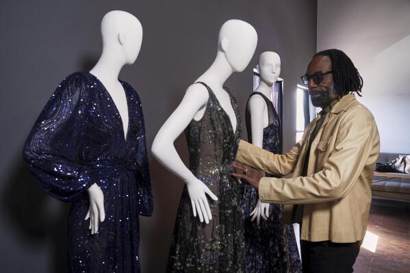 Fashion designer Kevan Hall pauses for a picture with his "Galaxy Collection" at his haute couture atelier in West Los Angeles Thursday, March 18, 2021. A year ago, Hall quickly moved away from his trademark gowns and cocktail dresses to caftans, tunics and pull-on pants. Now Hall is adding back some dressier looks, but he’s eliminating the full skirts and scaling back the beading in favor of simple gowns and dresses in knit and tulle fabrics. (AP Photo/Damian Dovarganes)