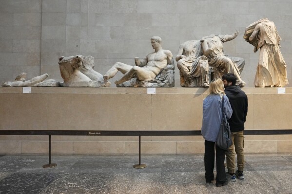 FILE - Visitors look at sculptures that are part of the Parthenon Marbles at the British Museum in London, Tuesday, Nov. 28, 2023. One of the world's most intractable cultural disputes has sprung to the fore again after a Turkish official cast doubt on the existence of proof cited by Britain that it had legally acquired the Parthenon Marbles, 2,500-year-old sculptures taken from the Acropolis in Athens. (AP Photo/Kirsty Wigglesworth, File)