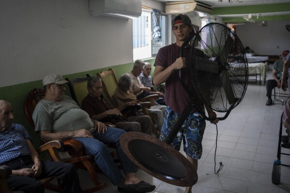 Humanitarian worker Roger Duvan Lagunes carries a fan into the Cogra, an elderly shelter, in Veracruz, Mexico, on June 16, 2024. (AP Photo/Felix Marquez, File)