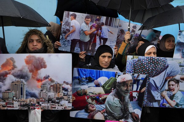 FILE - Palestinian Hamas supporters hold posters shows the Israeli bombardment on Gaza during a protest demanding that staff who were fired in the Gaza Strip over allegations that they took part in the Oct. 7, attack on southern Israel be returned to their jobs and that countries resume funding of the agency, in front of the United Nations Relief and Works Agency (UNRWA) headquarters in Beirut, Tuesday, Jan. 30, 2024. (AP Photo/Bilal Hussein, File)
