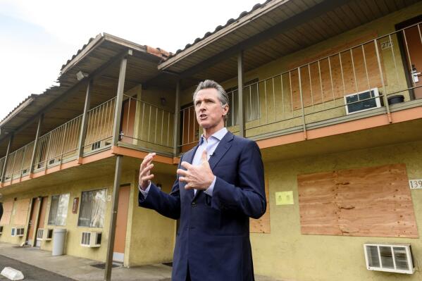 FILE - California Governor Gavin Newsom speaks with reporters while touring an inn being converted to interim housing for the homeless, on Jan. 13, 2022, in Santa Clara, Calif. California Gov. Gavin Newsom said Thursday, Nov. 3, 2022, he will delay $1 billion of spending to local governments because he says they are not being aggressive enough to curb homelessness in their communities. (AP Photo/Noah Berger, File)