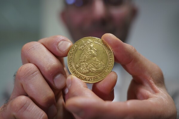 Vicken Yegparian, vice president of numismatics, Stack's Bowers Galleries, holds a golden coin once belonging to the collection of Danish king, Frederik VII, now part of L. E. Bruun's collection, in Zealand, Denmark, May 7, 2024. The vast coin collection of a Danish butter magnate is set to finally go to on sale a century after his death, and could fetch up to $72 million. Lars Emil Bruun, also known as L.E. Bruun, stipulated in his will that his 20,000-piece collection be safeguarded for 100 years before being sold. (AP Photo/James Brooks)