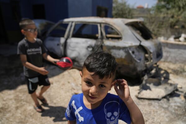 Palestinian boys play by their family's vehicle, which was burnt during an overnight attack by Israeli settlers and left several burnt vehicles and damaged homes, residents said, in the West Bank village of Bruqin, near Salfit, Friday, May 23, 2025. (AP Photo/Nasser Nasser)