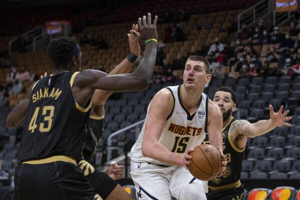 Denver Nuggets' Nikola Jokic (15) is defended by Toronto Raptors, including Pascal Siakam, left, and Fred VanVleet, right, during the second half of an NBA basketball game Saturday, Feb. 12, 2022, in Toronto. (Chris Young/The Canadian Press via AP)