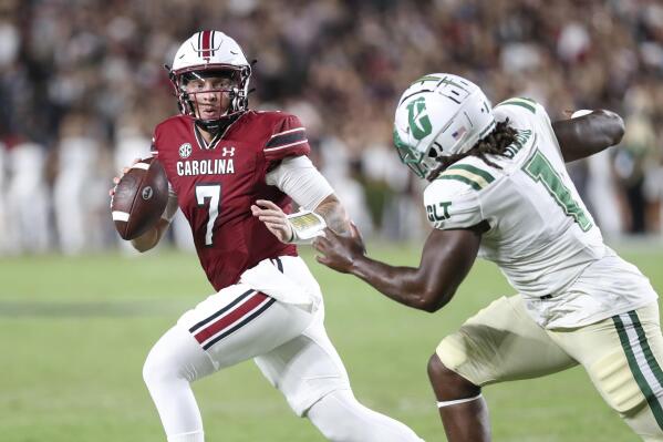 South Carolina quarterback Spencer Rattler (7) scrambles away from Charlotte defensive lineman Amir Siddiq (1) during the first half of an NCAA college football game on Saturday, Sept. 24, 2022, in Columbia, S.C. (AP Photo/Artie Walker Jr.)