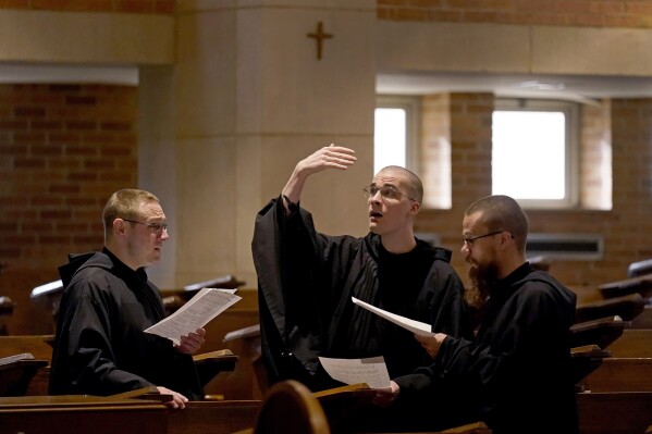 Brothers Leven Barton, left, Florian Rumpza, center, and Angelus Atkinson, sing in Latin during Catholic Mass at Benedictine College Sunday, Dec. 3, 2023, in Atchison, Kan. (AP Photo/Charlie Riedel)