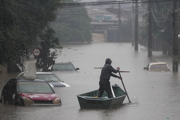 A man rows a boat on a street flooded by heavy rains, in Sao Leopoldo, Rio Grande do Sul state, Brazil, Saturday, May 11, 2024. (AP Photo/Andre Penner)