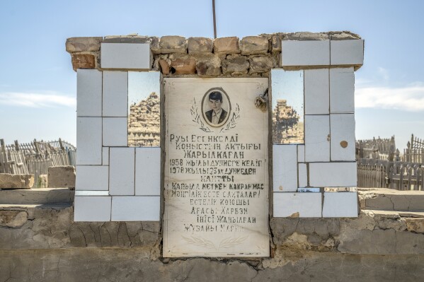 A man's photo is visible on his grave in a cemetery near the dried-up Aral Sea, on the outskirts of Muynak, Uzbekistan, Monday, June 26, 2023. (AP Photo/Ebrahim Noroozi)