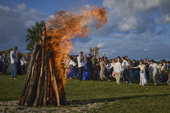 People dance in circle around a bonfire during a traditional midsummer celebration in Pyrohiv, Ukraine, outside of Kyiv, Saturday, June 21, 2025. (AP Photo/Efrem Lukatsky)