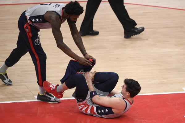 Washington Wizards forward Deni Avdija, bottom, reacts after he was injured during the first half of an NBA basketball game against the Golden State Warriors, Wednesday, April 21, 2021, in Washington. Also seen is Wizards center Jordan Bell (7). (AP Photo/Nick Wass)