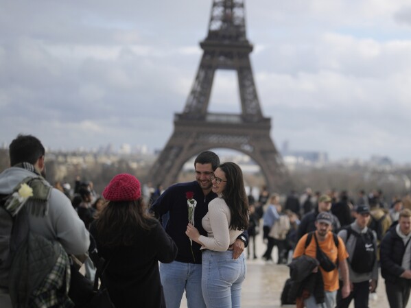 A couple pose for a photographer in front of the Eiffel Tower, during Valentine's day, in Paris, Wednesday, Feb. 14, 2024. (AP Photo/Thibault Camus)