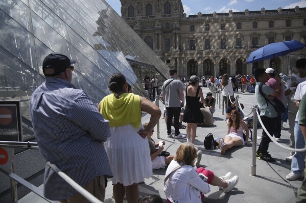 Tourists wait outside the Louvre museum which failed to open on time Monday, June 16, 2025 in Paris. (AP Photo/Christophe Ena)