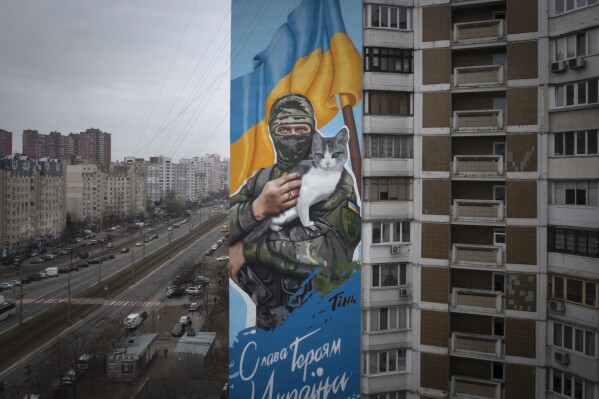 A mural depicts volunteer soldier Oleksiy Movchan holding a rescued cat moments before his death, on the wall of an apartment block in Kyiv, Ukraine, Thursday, Feb. 1, 2024. Writing on the mural reads: "Glory to Heroes of Ukraine". Movchan and three of his fellow soldiers rescued 11 civilians and the cat from under debris of a house ruined in the Russian rocket attack in the country's eastern Donetsk region, but he got hit by the shelling and was killed. (APPhoto/Efrem Lukatsky)